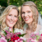 Glückliche Braut mit Trauzeugin an ihrer Hochzeit im Grünen