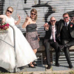 Cooles Hochzeitspaar mit Freunden posiert vor einem Graffiti